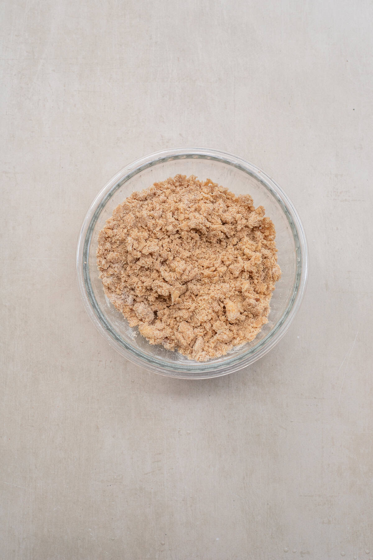 Freshly baked pumpkin coffee cake topped with pumpkin-spiced streusel and drizzled with a sweet glaze. A glass bowl with the brown sugar crumble.