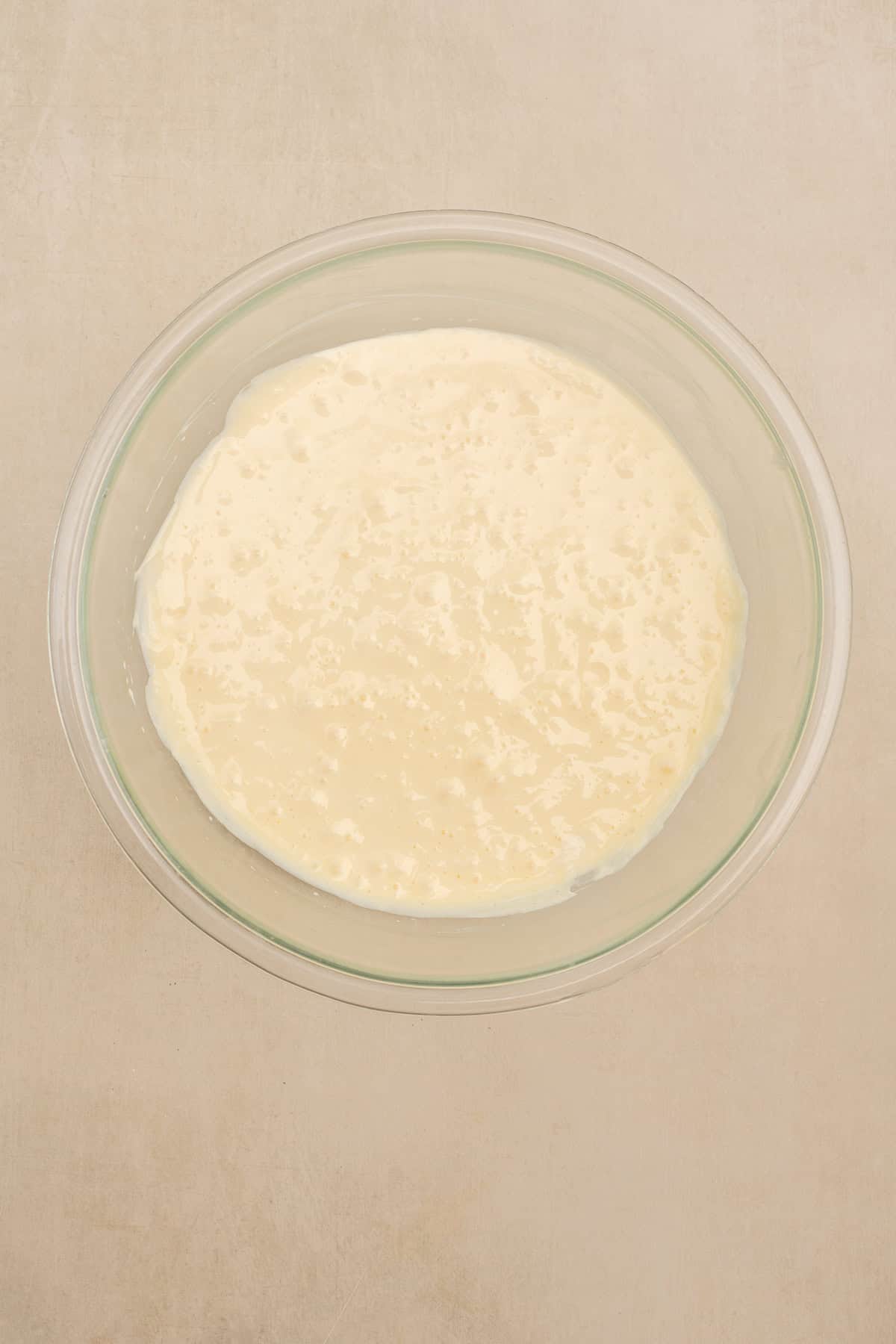 Buttery crumble topping sprinkled over blueberry cheesecake before baking. A glass bowl with the cheesecake filling.