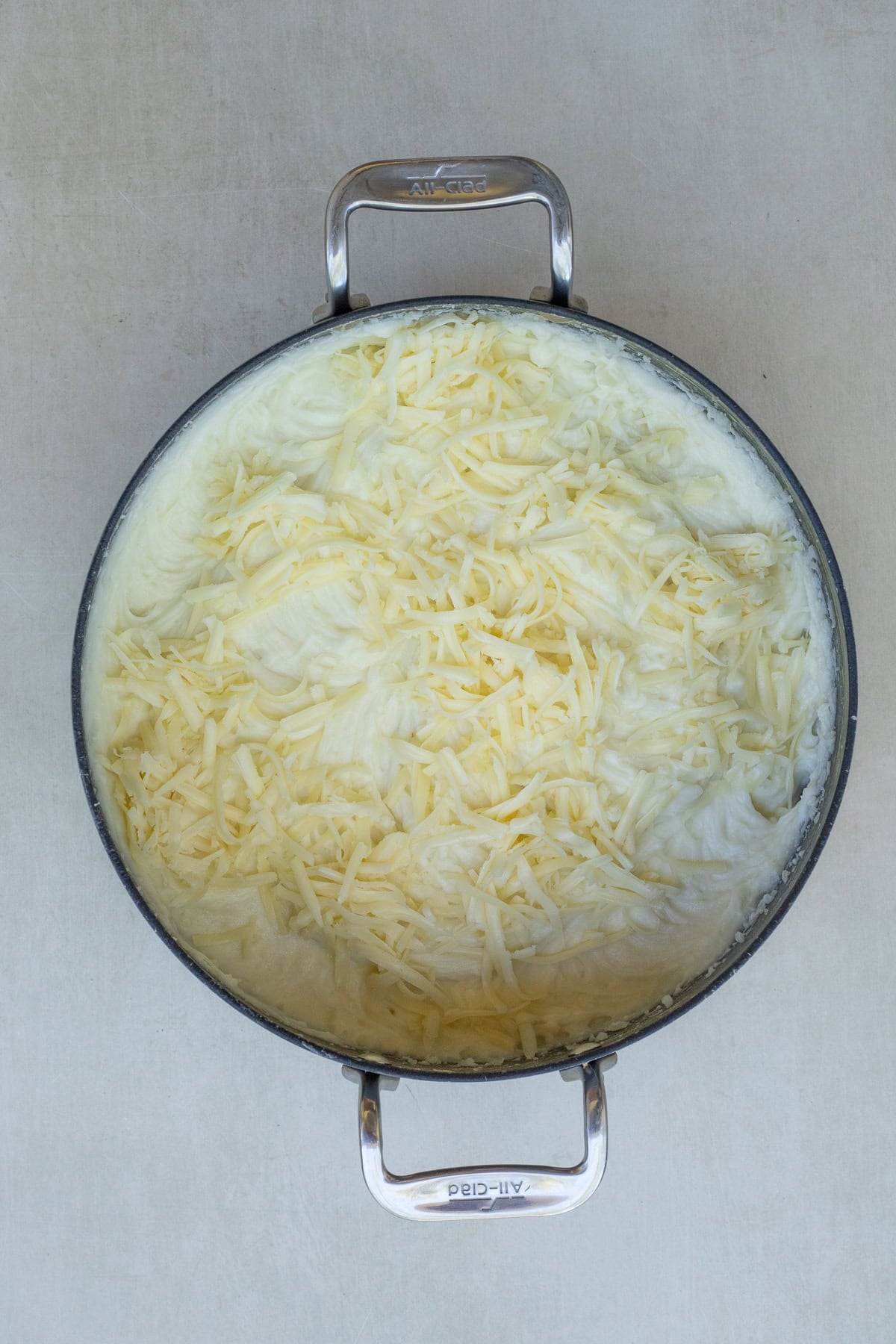Adding Shredded Cheese to Mashed Potatoes A pot with the creamy potatoes topped with cheese.