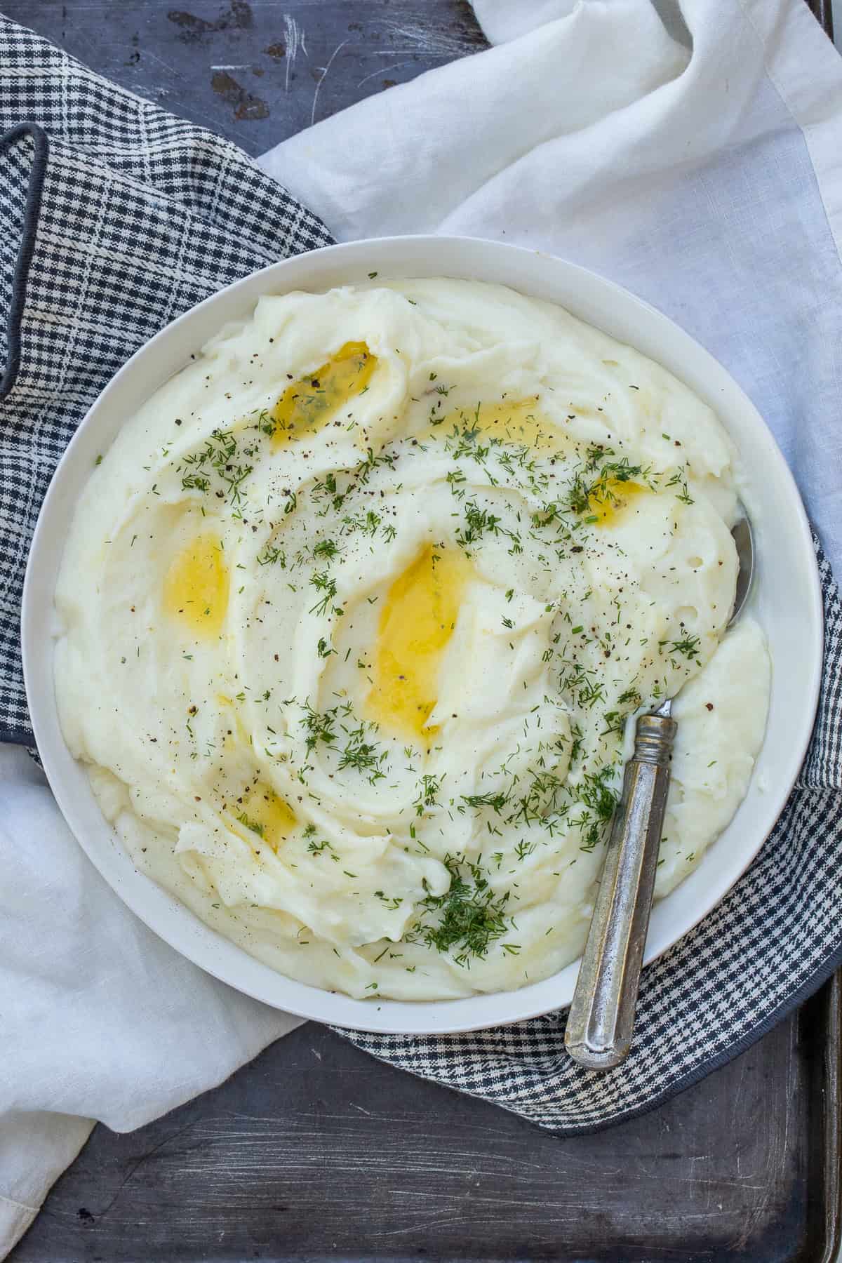 Easy Homemade Cheesy Mashed Potatoes A bowl of cheesy mashed potatoes with butter and chives.